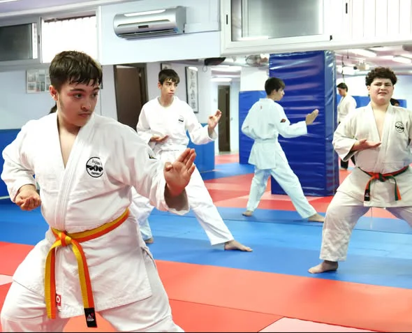Alumno de Jiu Jitsu de Hansu en posición de defensa en primer plano, con el grupo entrenando detrás