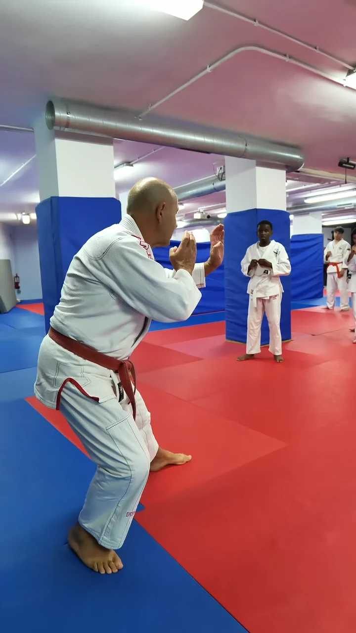 Jiu Jitsu en Hansu: un practicante en posición de guardia sobre el tatami, con alumnos entrenando al fondo